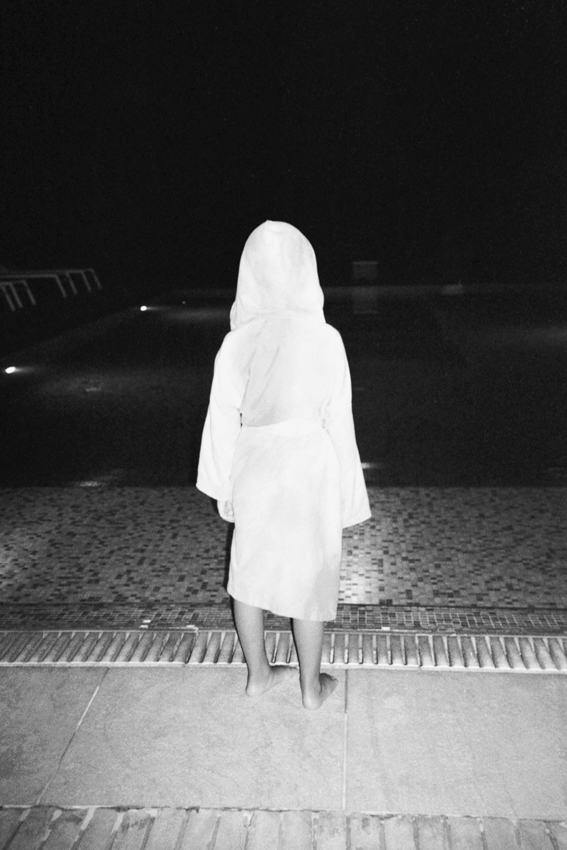 Figura di spalle davanti a una piscina di notte