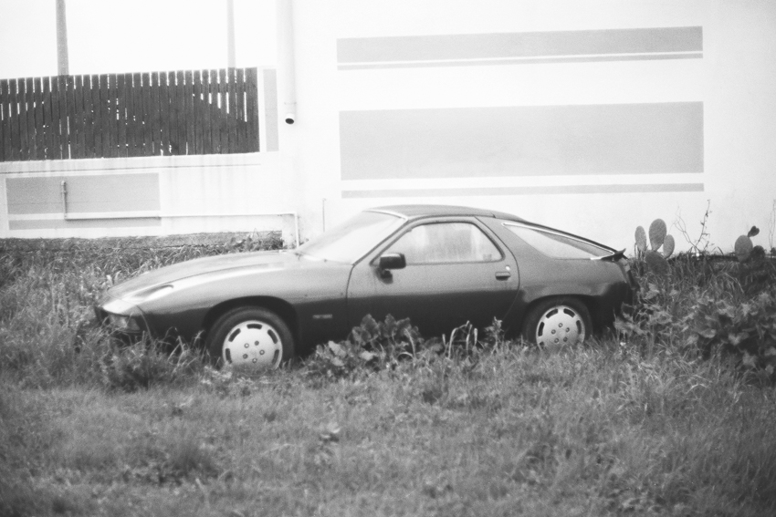 Automobile abbandonata nell'erba davanti a un edificio